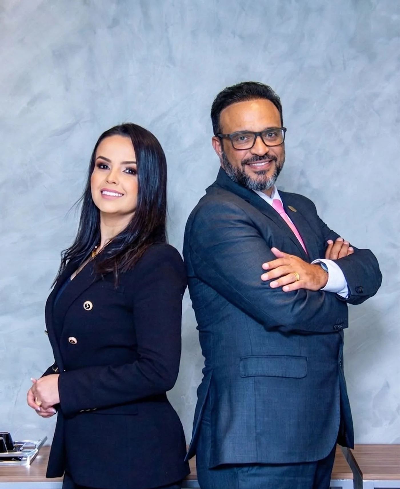 Glaucia Aguilar e Leandro Lopes Aguilar, de costas um para o outro, no escritório